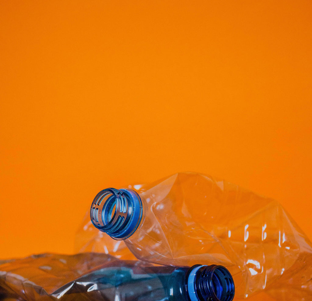 A photo of plastic bottles on an orange background.